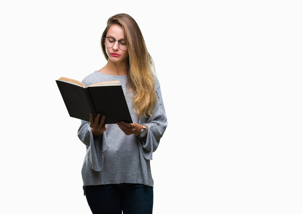 Νέοι όμορφη ξανθιά γυναίκα διαβάζοντας ένα βιβλίο πέρα από το απομονωμένο υπόβαθρο με αυτοπεποίθηση έκφραση στο έξυπνο πρόσωπο σκέφτεται σοβαρά - Φωτογραφία, εικόνα