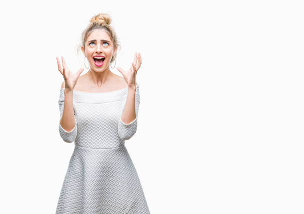 Young beautiful blonde and blue eyes woman over isolated background crazy and mad shouting and yelling with aggressive expression and arms raised. Frustration concept. - Photo, Image