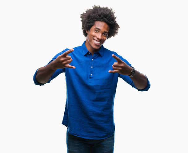 afroamerikanischer Mann über isoliertem Hintergrund, der mit verrücktem Gesichtsausdruck Rocksymbole mit erhobenen Händen macht. Musikstar. Schweres Konzept. - Foto, Bild