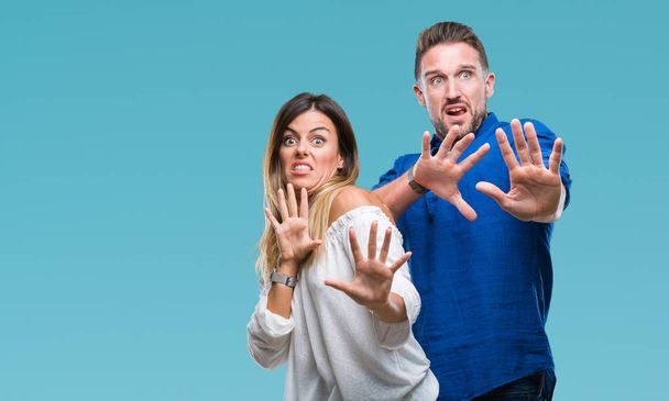 Young couple in love over isolated background afraid and terrified with fear expression stop gesture with hands, shouting in shock. Panic concept. - Photo, Image