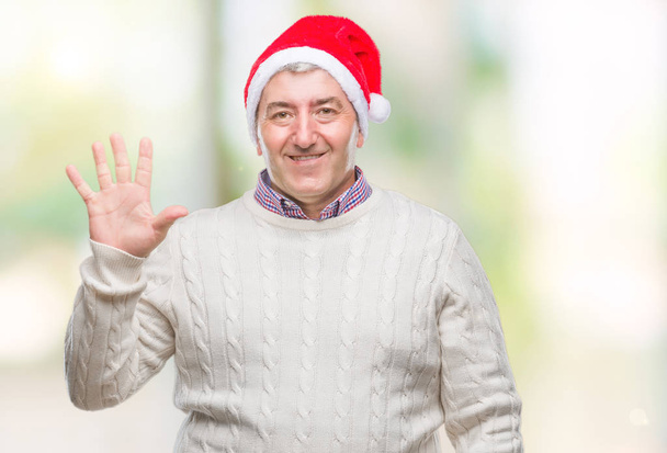 Bell'uomo anziano che indossa il cappello di Natale su sfondo isolato mostrando e indicando con le dita il numero cinque, sorridendo fiducioso e felice
. - Foto, immagini