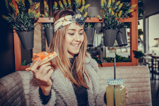 Hermosa joven feliz comiendo una rebanada de pizza y bebiendo limonada en el restaurante
 - Foto, imagen