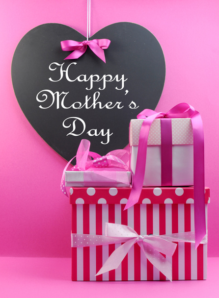 Empilement de belles rayures roses et de cadeaux à pois avec tableau noir en forme de coeur avec message de la fête des mères heureuses
. - Photo, image