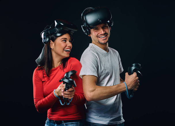 Onnellinen pari pelaajat ohjaimet ja VR kuulokkeet
. - Valokuva, kuva