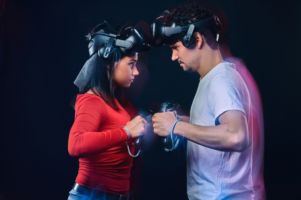Couple of pro gamers with VR headsets participate in the game battle. Photo with light effect. - Photo, Image