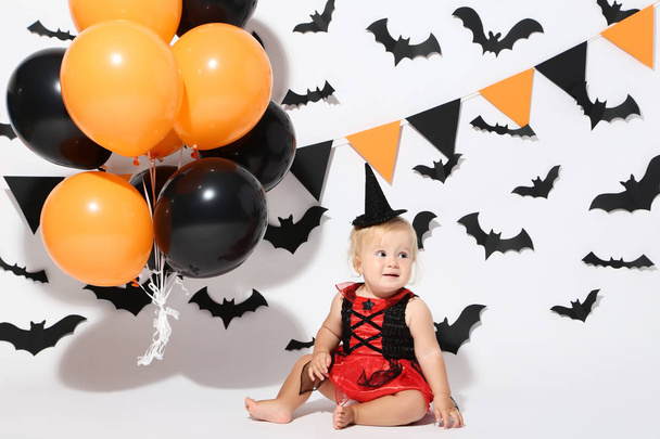 Baby girl in halloween costume and balloons on white background - Photo, image