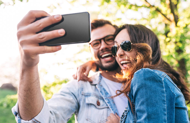 Cheerful couple taking selfie in park - Foto, afbeelding