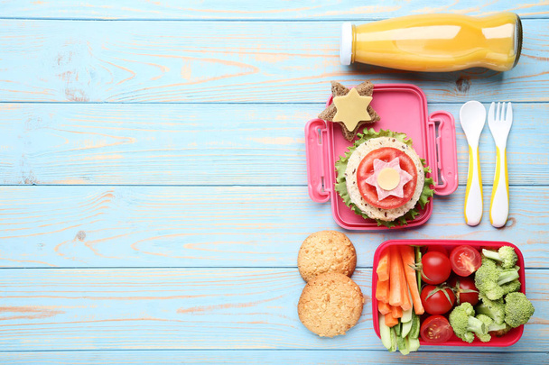 School lunch box with vegetables and bottle of juice on blue wooden table - Photo, Image