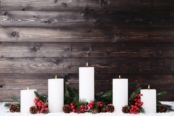 Белые рождественские свечи с ветвями елки и шишками на деревянном фоне
 - Фото, изображение