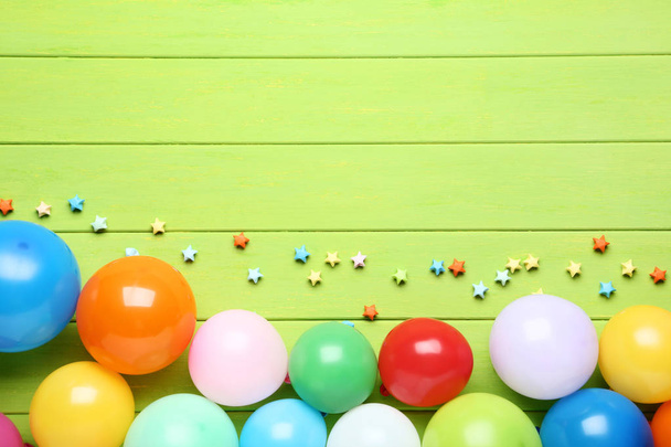 Colorful balloons with paper stars on green wooden table - Foto, afbeelding