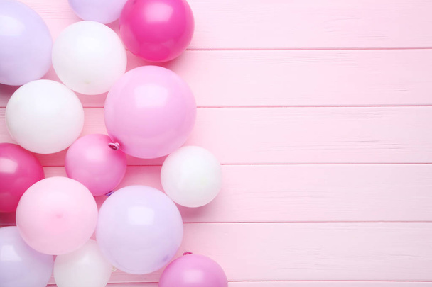 Colorful balloons on pink wooden table - Fotoğraf, Görsel