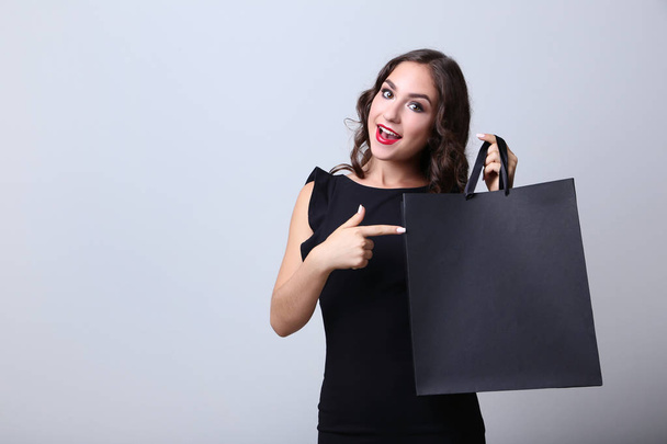 Happy woman with shopping bag on grey background - Фото, зображення