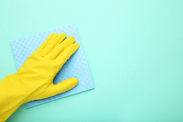Hand in glove with sponge on mint background - Fotó, kép