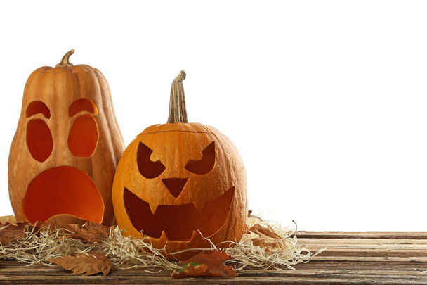Halloween pumpkins with dry leafs on brown wooden table - Fotó, kép