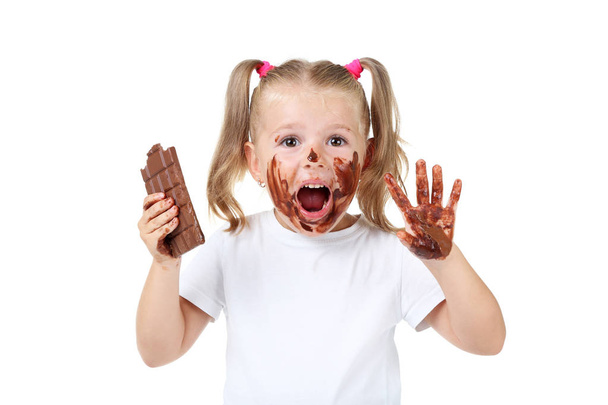 Happy little girl eating chocolate on white background - Zdjęcie, obraz