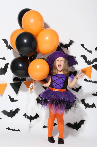 Young girl in halloween costume with balloons on white background - Fotó, kép