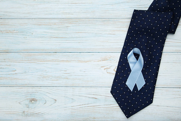 Blue ribbon with necktie on wooden table. Prostate cancer concept - Φωτογραφία, εικόνα