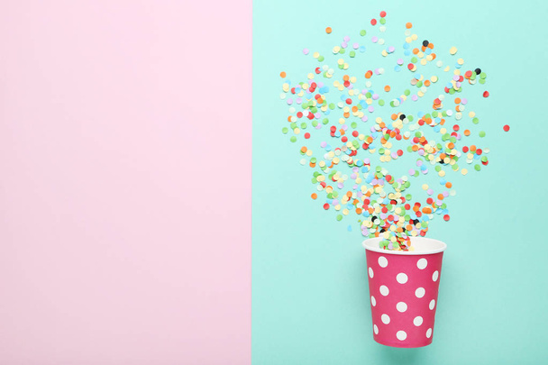 Pink paper cup with confetti on colorful background - Zdjęcie, obraz