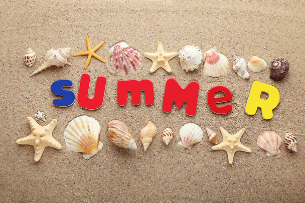 Inschrijving zomer door gekleurde letters met schelpen op het strand zand - Foto, afbeelding