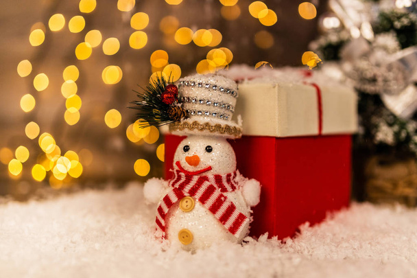 Χριστουγεννιάτικη διακόσμηση σε φόντο ξύλινη με χιονάνθρωπο, το χιόνι και τα φώτα στο παρασκήνιο ευτυχισμένο το νέο έτος. - Φωτογραφία, εικόνα