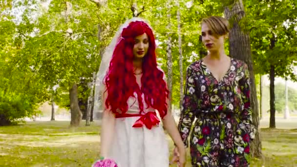 Lesbische bruiloft. De bruid en bruidegom lopen in het park - Video
