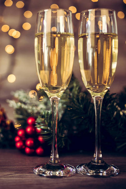 Christmas decoration with two glasses of champagne and lights on a wooden background, Happy New Year. Celebration. Selective focus and small depth of field. - 写真・画像