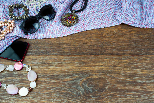 Conjunto de accesorios para mujer joyas móviles gafas pulsera de perlas. Madera oscuro fondo vista superior plano lay copia espacio
 - Foto, Imagen
