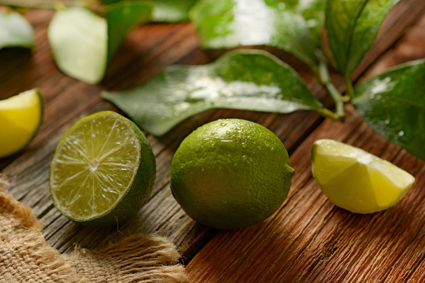 lime fruits with leaves on wooden table - tropical fruit with antioxidant properties - closeup - Foto, Imagen