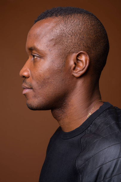 茶色の背景に対する若いアフリカ人間のスタジオ撮影 - 写真・画像