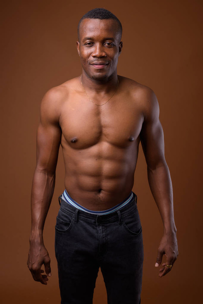 Giovane uomo africano senza camicia contro sfondo marrone
 - Foto, immagini