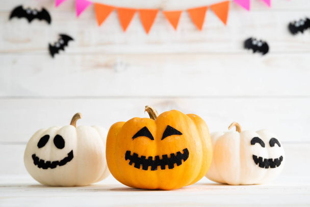White and yellow ghost pumpkins with witch hat on white wooden borad background with bat. halloween concept. - Foto, Imagen