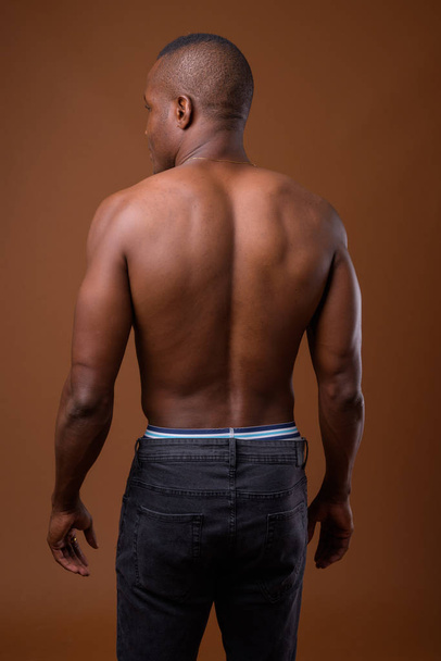 Giovane uomo africano senza camicia contro sfondo marrone
 - Foto, immagini
