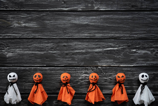 Vista superior de manualidades de Halloween, fantasma de papel blanco y naranja sobre fondo de madera blanco y negro con espacio de copia para texto. concepto de Halloween
. - Foto, Imagen
