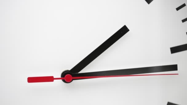 ρολόι με κόκκινα και μαύρα βέλη σε λευκό φόντο, όπως η έννοια του χρόνου σπατάλης και της εργασίας  - Πλάνα, βίντεο
