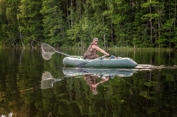 Rybář loví v veslice na krásné jezero - Fotografie, Obrázek