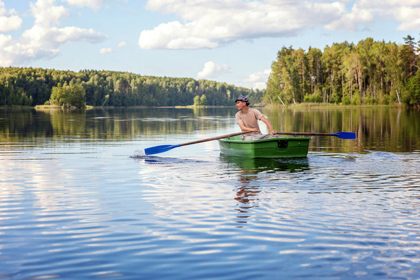 Un pescador está pescando en un barco de madera en un hermoso lago
 - Foto, imagen