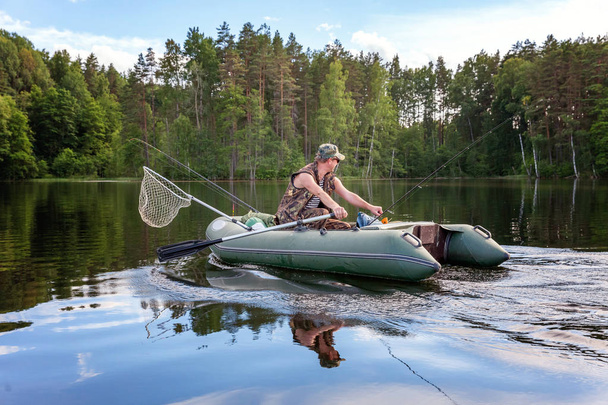 Um pescador está pescando em um barco em um belo lago
 - Foto, Imagem