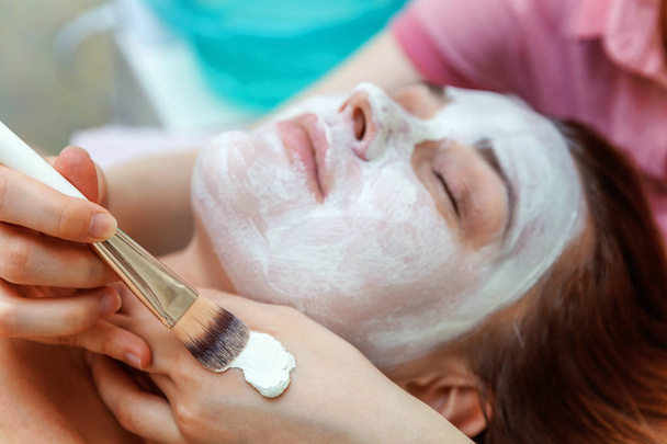 spa, resort, schoonheid en gezondheid concept - mooie vrouw in spa salon krijgen gezichtsbehandeling - Foto, afbeelding