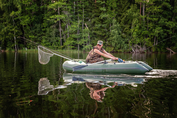Um pescador está pescando em um barco em um belo lago
 - Foto, Imagem