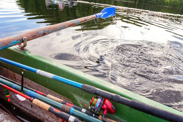 Close-up van oar peddel van roeiboot bewegen in water op groen meer met rimpelingen - Foto, afbeelding