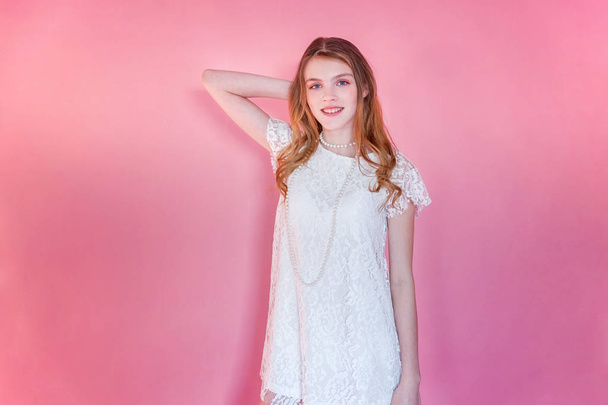 Ευτυχισμένος εφηβικό κορίτσι που χαμογελά. Closeup πορτρέτο ευτυχισμένη θετική κοπέλα φορώντας λευκό φόρεμα στέκεται στο ροζ πολύχρωμες παστέλ μοντέρνα σύγχρονη μόδα καρφίτσα-επάνω υπόβαθρο. Ευρωπαία γυναίκα. Γλώσσα του σώματος του προσώπου έκφραση θετικό ανθρώπινο συναίσθημα - Φωτογραφία, εικόνα