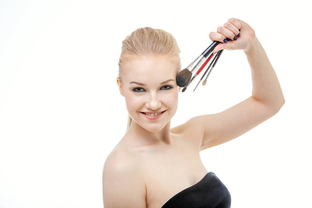 Portrait of the beautiful woman with make-up brushes near attractive face. Adult girl posing over white background - Foto, imagen