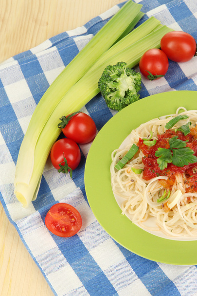 Tasty spaghetti with sauce and vegetables on plate on wooden table close-up - Photo, Image