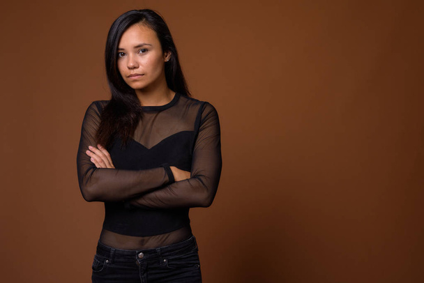茶色の背景に対して若いアジア女性のスタジオ撮影 - 写真・画像