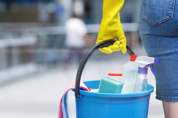 Uma mulher carregando um balde cumpriu com a equipe química em sua mão em luva de borracha. O conceito é a popularidade do serviço de limpeza
. - Foto, Imagem