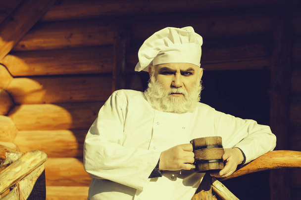 bearded cook with wooden cup - Foto, imagen
