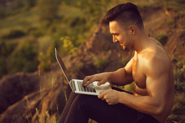 Sorrindo homem muscular com laptop ao ar livre
 - Foto, Imagem