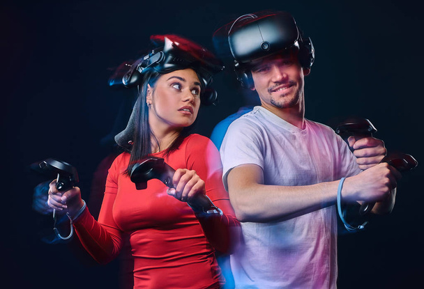 Portrait d'un jeune couple caucasien posant avec casques VR et contrôleurs
. - Photo, image