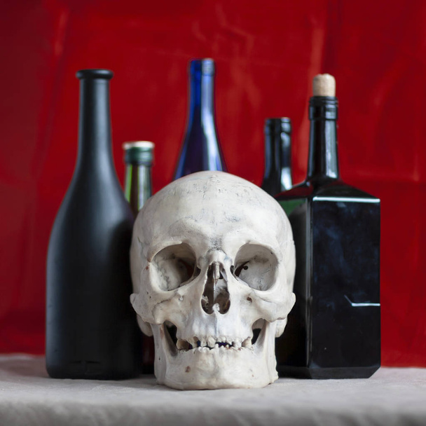 Skull on the background of alcohol bottles. The concept: the harmfulness of alcohol, death from alcohol. - Valokuva, kuva