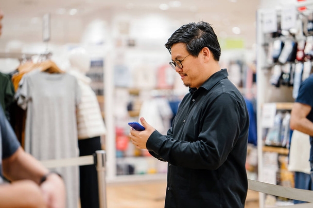 young man in shop choosing clothes - Foto, Imagen